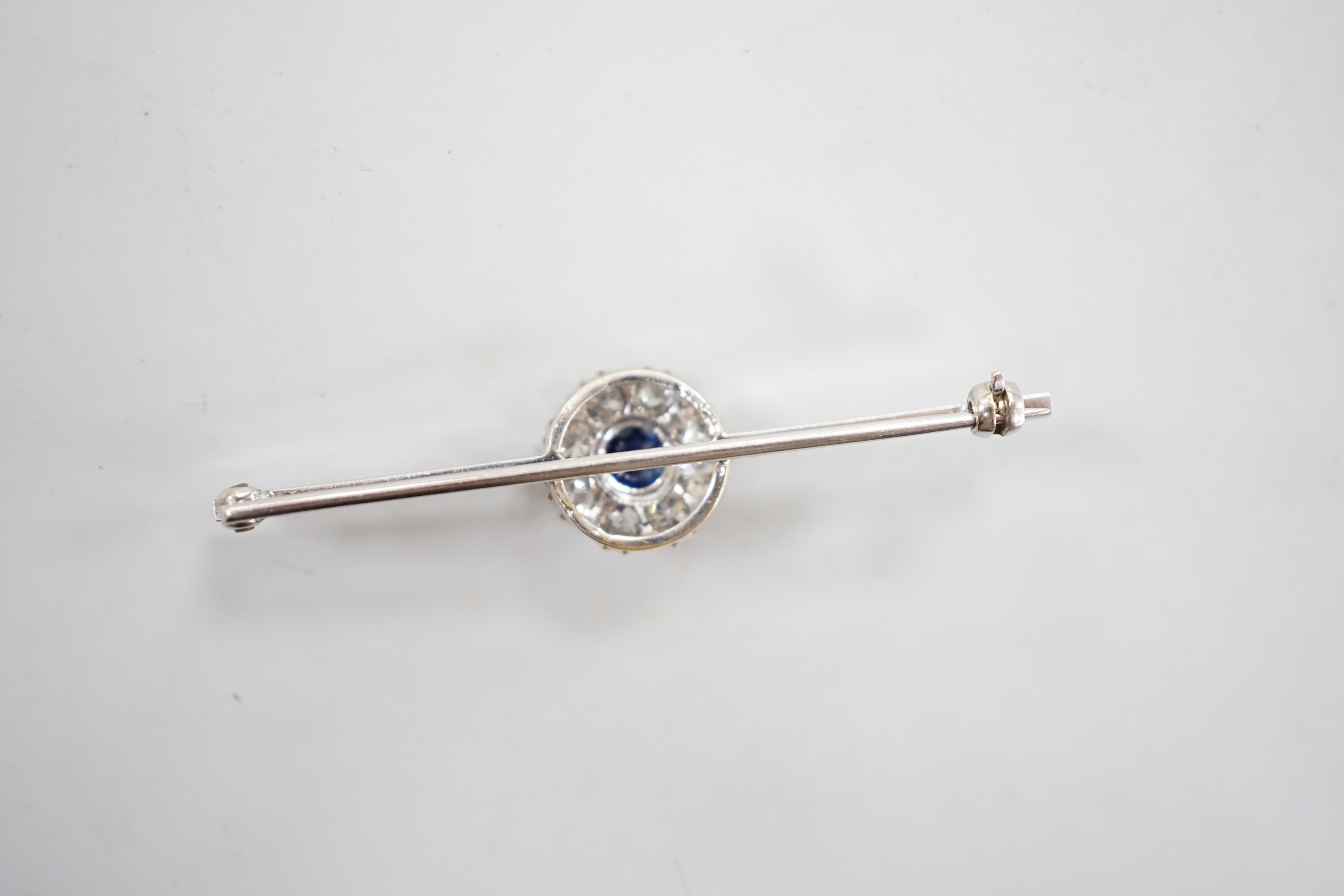 A mid 20th century white metal, sapphire and diamond cluster set bar brooch, 55mm, gross weight 4.5 rams.
